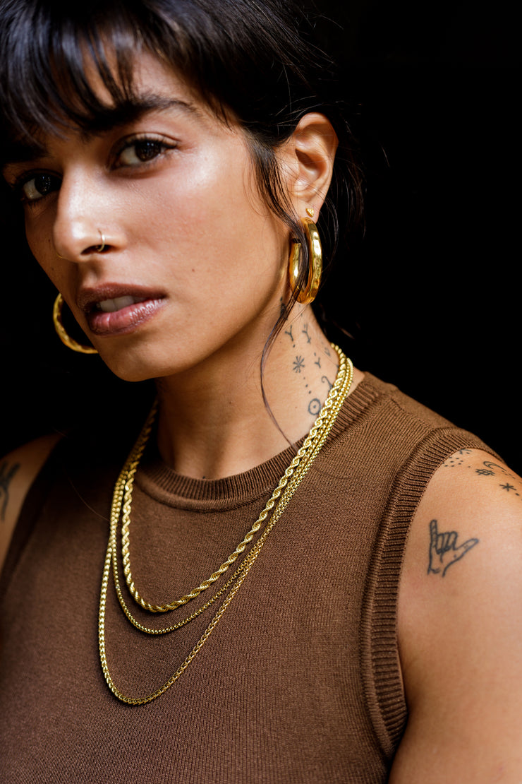 Unisex wheat chain handcrafted in brass. 1 micron gold plated necklace suited for men and women. Designed in Goa and handmade in Jaipur. Armeen layers the Tonca Chromosome Chain, Moira Box Chain and Aldona Chain. 